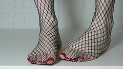 Painted red toenails in black fishnet pantyhose tights Thumb